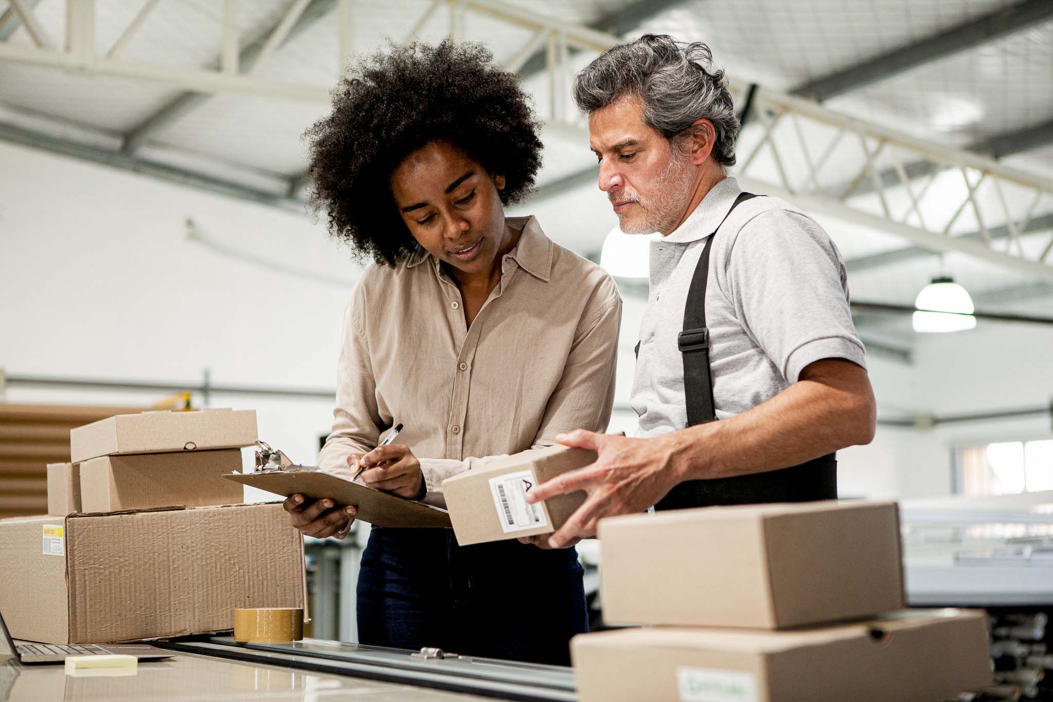 Portrait of warehouse colleagues preparing packages for shipping during daytime