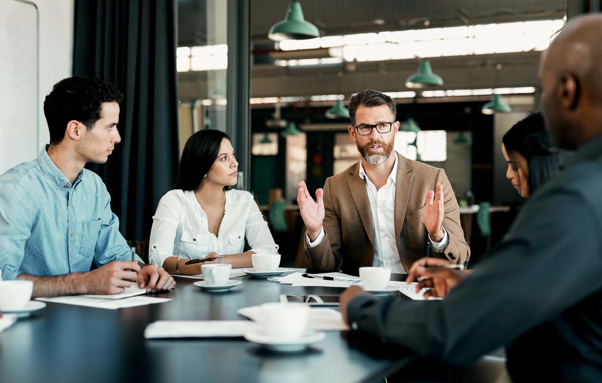 Business people, meeting and planning in team conference for marketing strategy, ideas and discussion at the office. Group of diverse corporate employee workers in teamwork conversation for sales